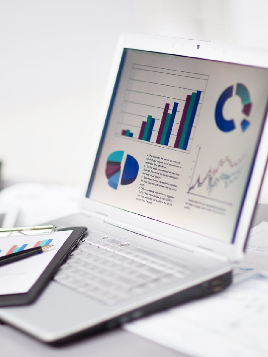 Laptop on desk with positive stats and colored graphs on the screen for commercial real estate appraisals and valuations